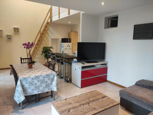 a living room with a flat screen tv and a table at Maison Proche Gare in Neufchâteau