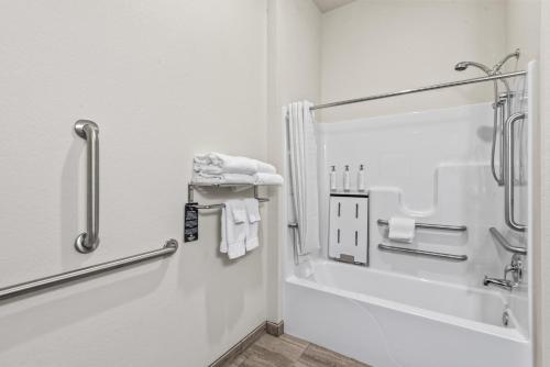 a bathroom with a tub and a shower with towels at Cobblestone Hotel & Suites Waukesha West Milwaukee in Waukesha