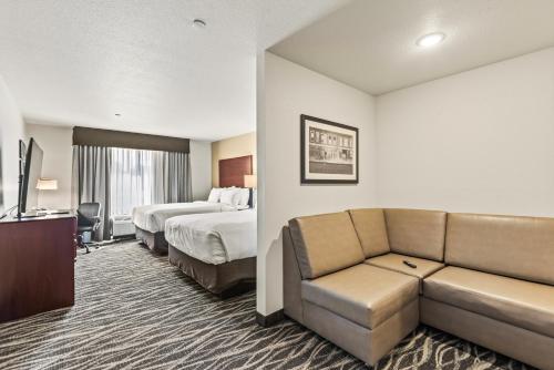 a hotel room with a couch and a bed at Cobblestone Hotel & Suites Waukesha West Milwaukee in Waukesha