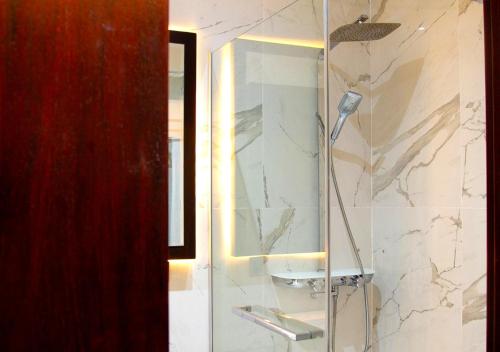 a bathroom with a shower with a sink and a mirror at Hôtel La Villa Racine in Dakar