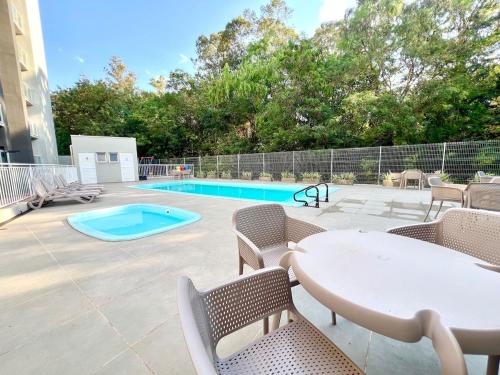 a patio with a table and chairs and a pool at Apartamento Inteiro - 2 Quartos com AC - Wifi 1000mb - Piscina - 1 Vaga de Garagem - Elevador - Sacada Gourmet - Indicado para Grupos, Hospedes a Trabalho, Família e Pets in Toledo