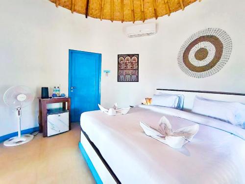 a bedroom with a large white bed with a blue door at Oasi Bungalow Gili Air in Gili Islands