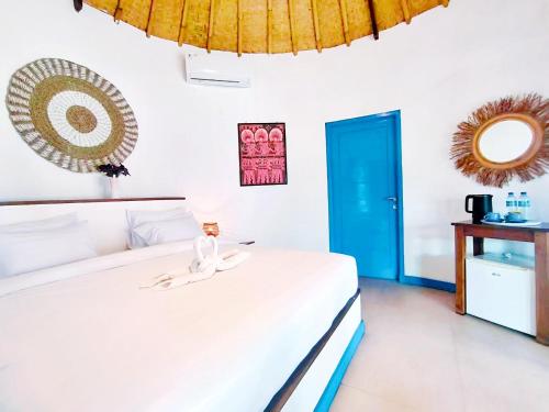 a bedroom with a white bed and a blue door at Oasi Bungalow Gili Air in Gili Islands