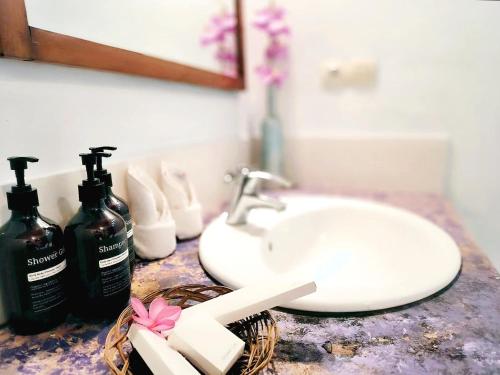a bathroom counter with a sink and two bottles of soap at Oasi Bungalow Gili Air in Gili Islands