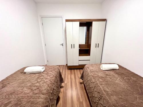 a room with two beds and a hallway with two doors at Apartamento Inteiro - 2 Quartos com AC - Wifi 1000mb - Piscina - 1 Vaga de Garagem - Elevador - Sacada Gourmet - Indicado para Grupos, Hospedes a Trabalho, Família e Pets in Toledo