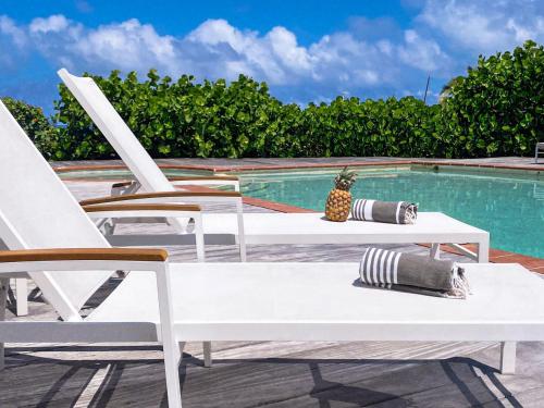 a pool with two lounge chairs and a table and a pineapple at Villa Olive Sea View Cocoon in Oyster Pond in Oyster Pond