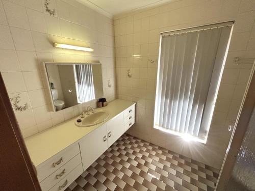 ein Badezimmer mit Waschbecken, Spiegel und Fenster in der Unterkunft Dukes of Yorkes - Wallaroo Beach Frontage - Entire Home in Wallaroo