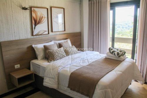 a bedroom with a large bed and a window at Igaratá: refúgio em meio a natureza com piscina in Igaratá