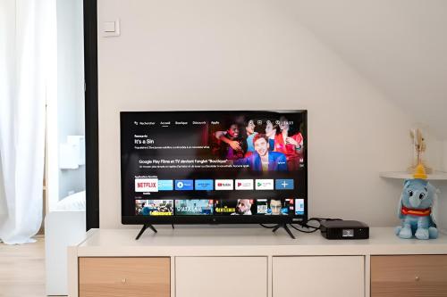 a flat screen tv sitting on top of a dresser at Le Délicat - Cozy - Disney 5min - Free Parking in Magny-le-Hongre