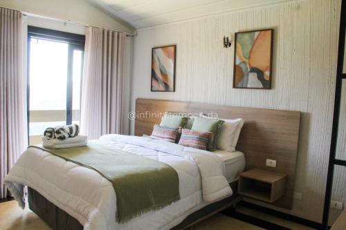 a bedroom with a large bed and a window at Igaratá: refúgio em meio a natureza com piscina in Igaratá