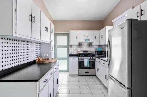a kitchen with white cabinets and a stainless steel refrigerator at Las Palmas Beach House with Private Pool and Pool Table in Ensenada