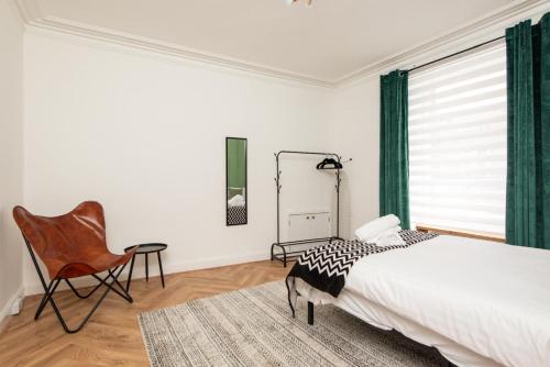 a bedroom with a bed and a chair and a mirror at Northcote apartment in Hawick