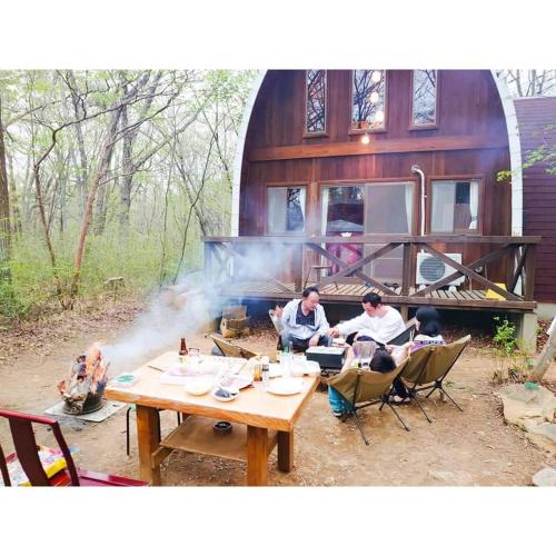 a group of people sitting around a fire pit at 那須クイーンズマウンテン 動物王国への拠点 ペット歓迎 温泉完備 一棟ログハウス 超体験型 貸別荘 ファミリーリゾート 乗馬 釣り ふれあい動物園 那須 in Nasu-yumoto