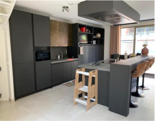 a kitchen with black cabinets and a kitchen island with chairs at Spectacular 3Floor Town House Nearby CityCenter in Rotterdam