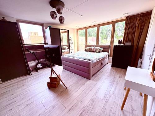 a room with a bed and a desk and windows at Spectacular 3Floor Town House Nearby CityCenter in Rotterdam