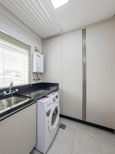 a kitchen with a washing machine and a sink at Melhor Apartamento centro Pomerode, perto de tudo in Pomerode