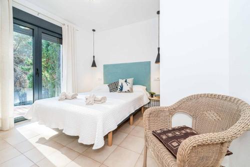 a white bedroom with a bed and a chair at Villa Abeto in El Tosalet