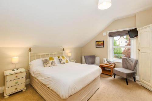 a bedroom with a bed and a chair and a window at Woodside B & B in Keswick