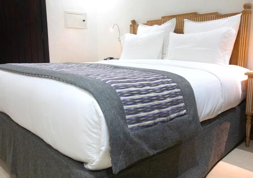 a large bed with white sheets and a blanket at Hôtel La Villa Racine in Dakar