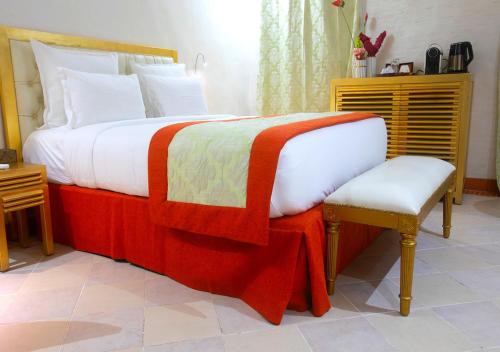 a bedroom with a large bed with a chair and a bed sqor at Hôtel La Villa Racine in Dakar