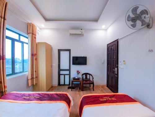 a hotel room with two beds and a tv at Khách sạn Thu Nga in Mai Chầu