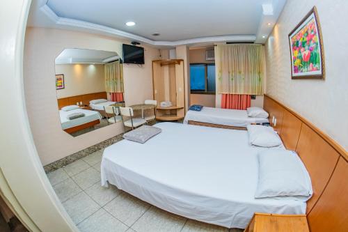 a hotel room with two beds and a mirror at Hotel Copamar in Rio de Janeiro