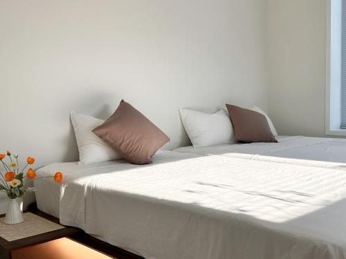 Una cama con sábanas blancas y almohadas en una habitación. en Private Rooftop Stay, en Gyeongju