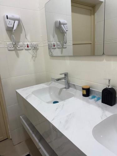 Un baño con un lavabo blanco y un espejo. en شقق لينا الخاصة, en Hail