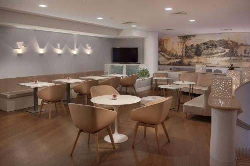 a restaurant with tables and chairs and a flat screen tv at NH Genova Centro in Genova