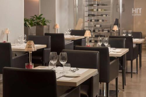 a restaurant with empty tables and chairs with wine glasses at NH Genova Centro in Genova