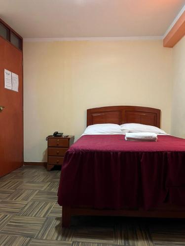 a bedroom with a bed with a red bedspread at lucero real hotel tacna 3 in Tacna