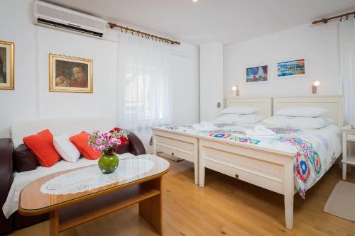 a white bedroom with a bed and a couch at Apartments Sunce in Split