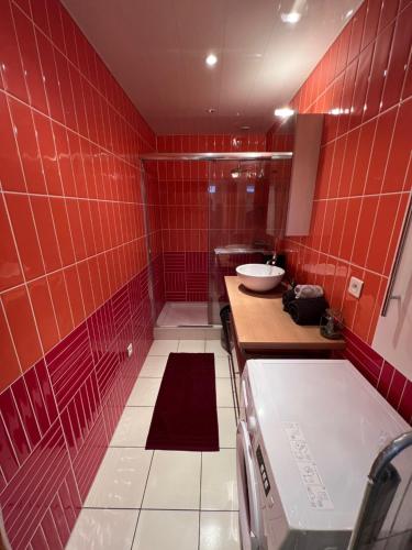 un bagno piastrellato rosso con lavandino e vasca di Grand T3 avec parking privé, centre & caves à champagne a Reims