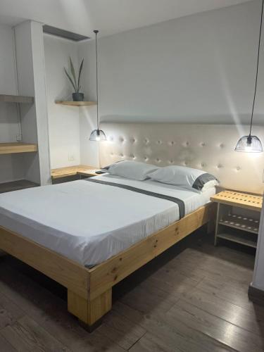 a large bed in a bedroom with two pendant lights at Hotel 42 Avenida in Palmira