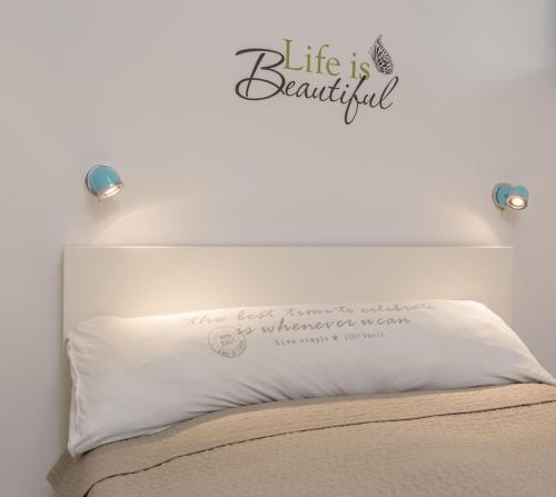 a bed with a white pillow with a sign that says life is beautiful at Alma in Caesarea