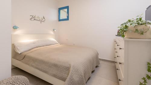 a white bedroom with a bed and a dresser at Alma in Caesarea