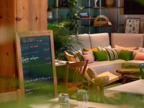 a room with a couch and a table with a chalkboard at Greet Hotel Colmar in Colmar