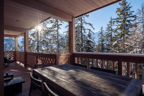a room with a table and chairs on a balcony with trees at Antarès ORION 202 - luxury apartment ski inski out in Méribel