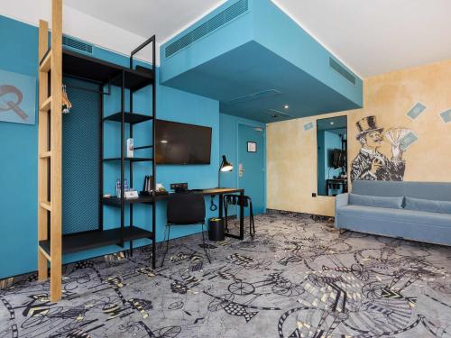 a room with a blue wall with a desk and a couch at ibis Styles Szczecin Stare Miasto in Szczecin
