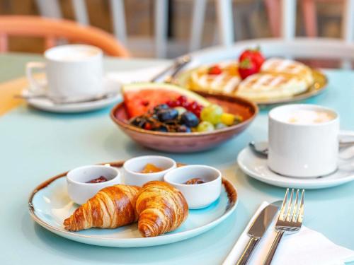 a table with a plate of croissants and a tray of food at ibis Styles Szczecin Stare Miasto in Szczecin