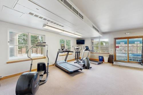 a gym with treadmills and ellipticals in a room with windows at Blue River Escapade in Breckenridge
