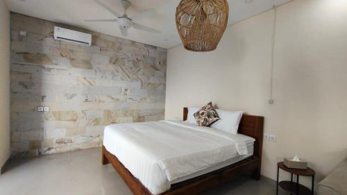 a bedroom with a bed and a stone wall at Villa Telge in Sanur