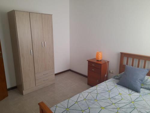 een slaapkamer met een bed en een houten kast bij Complejo Vélez Sarsfield 185 in Bell Ville