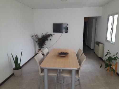 een eettafel met stoelen en een tv aan de muur bij Complejo Vélez Sarsfield 185 in Bell Ville