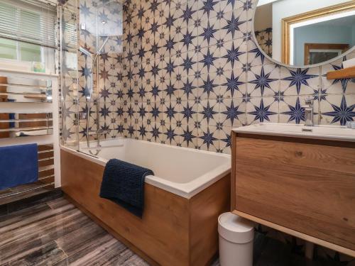 a bathroom with a tub and a sink and a mirror at Rookery Cottage in Lynton
