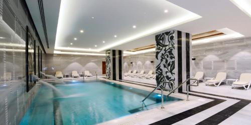 a pool in a house with chairs and a table at Crowne Plaza Bursa Convention Center & Thermal Spa by IHG in Bursa