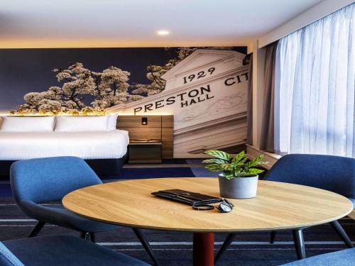 a hotel room with a bed and a table and chairs at Novotel Melbourne Preston in Melbourne