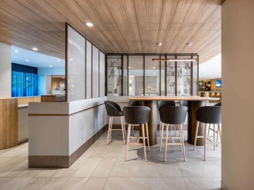 a kitchen with a bar with chairs and tables at Novotel Melbourne Preston in Melbourne