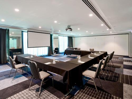 a conference room with a long table and chairs at Novotel Melbourne Preston in Melbourne