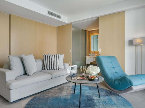 a living room with a white couch and a blue chair at Mövenpick Resort Al Marjan Island in Ras al Khaimah